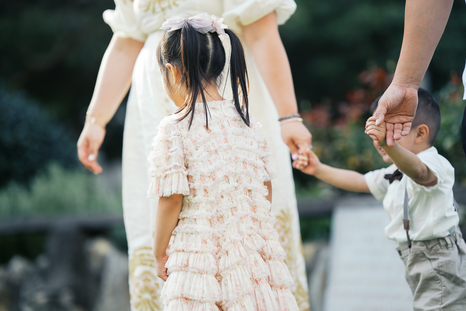 Young family holding hands, walking in the garden