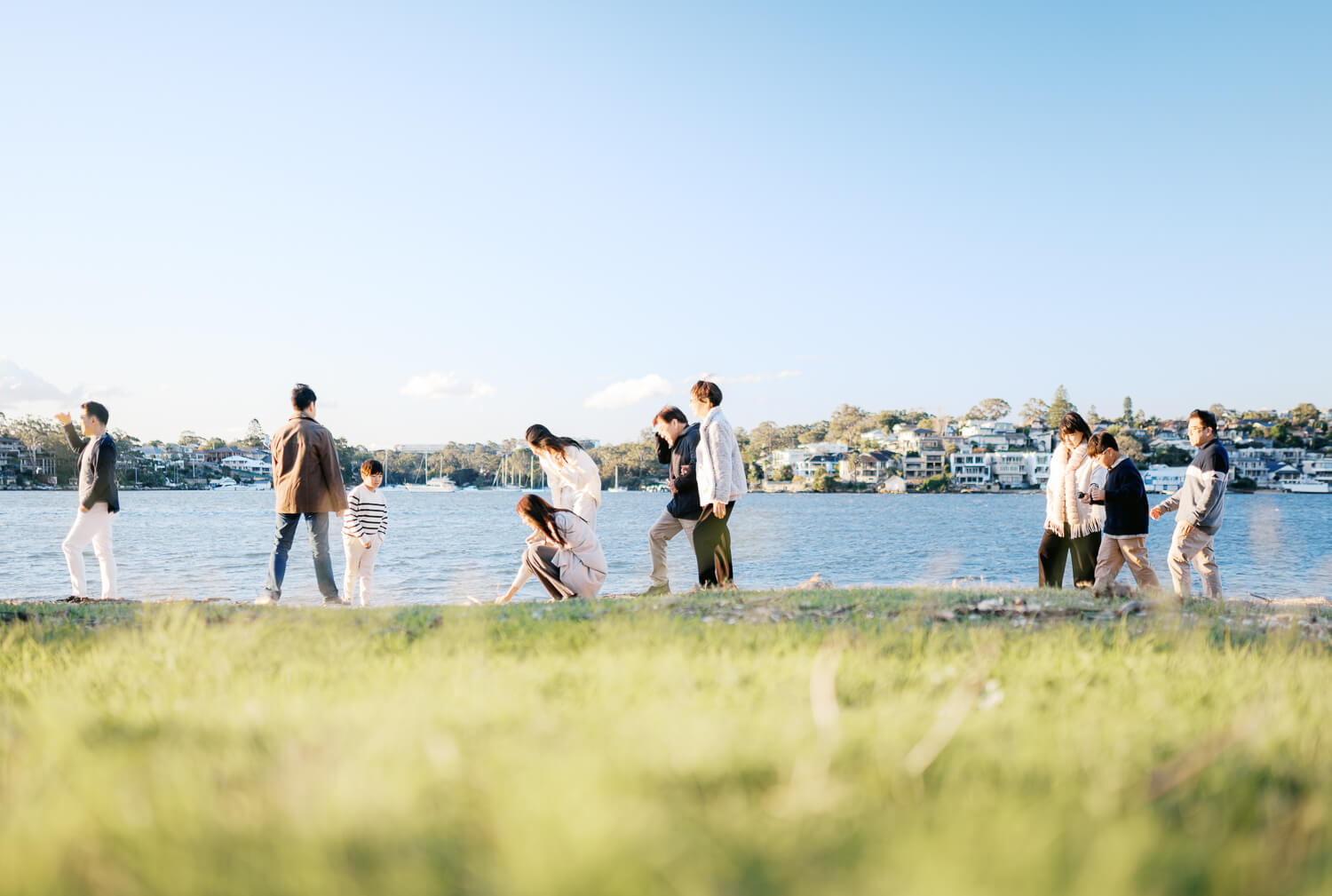 Extended family basking in the sun during afternoon walk by the water in winter