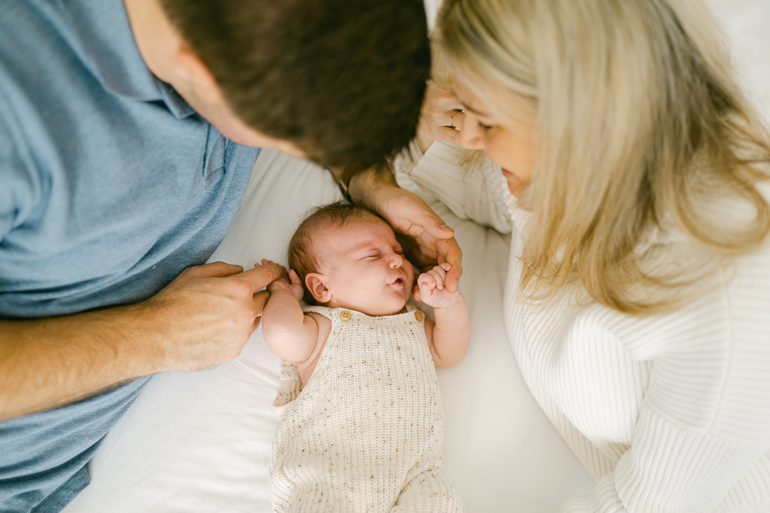 Newborn baby in bed with new parents at home in morning lights