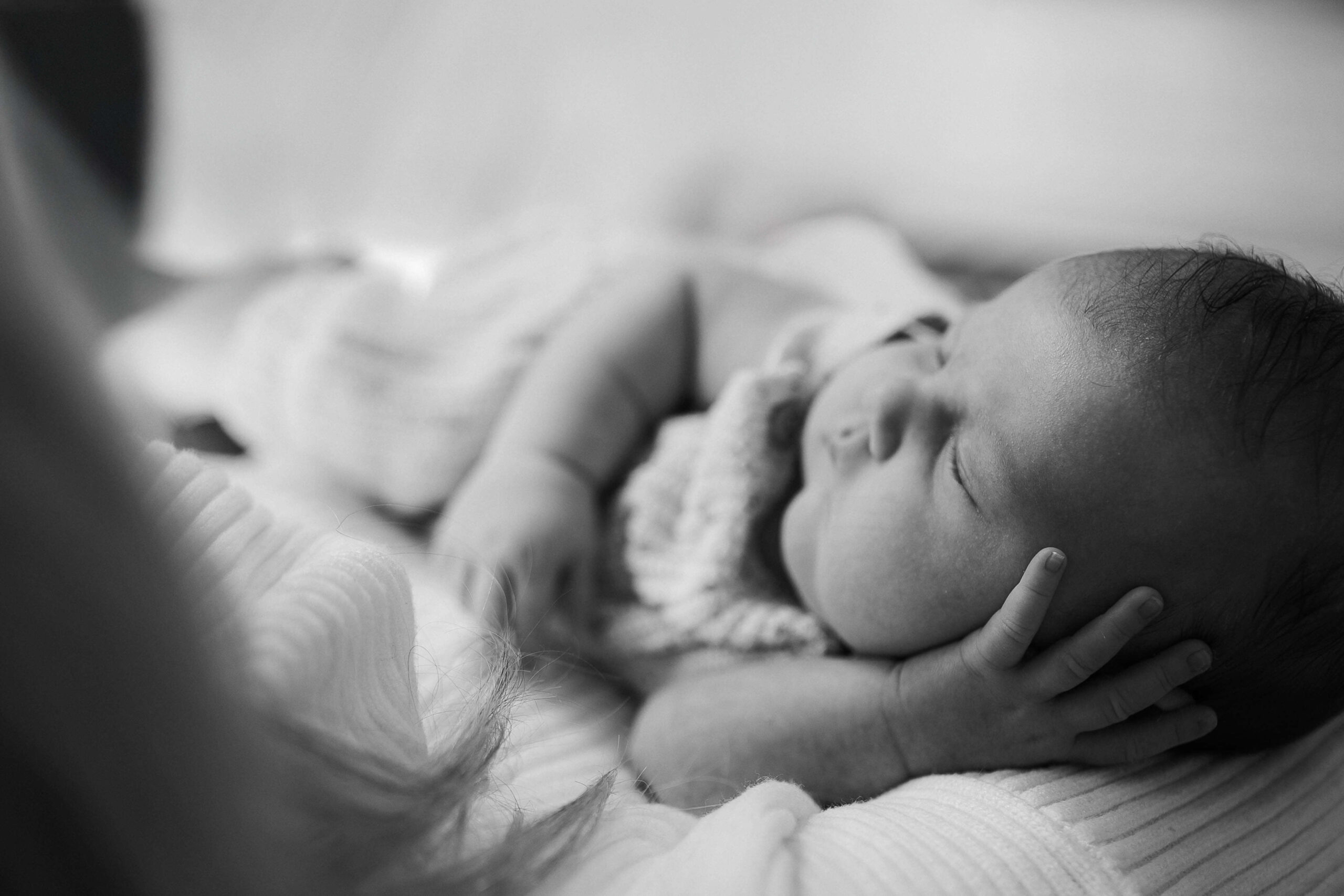 Newborn baby deep sleeping in mum's hand in black and white
