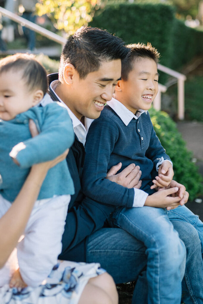 Dad snuggling close to kids sharing a laugh in the garden