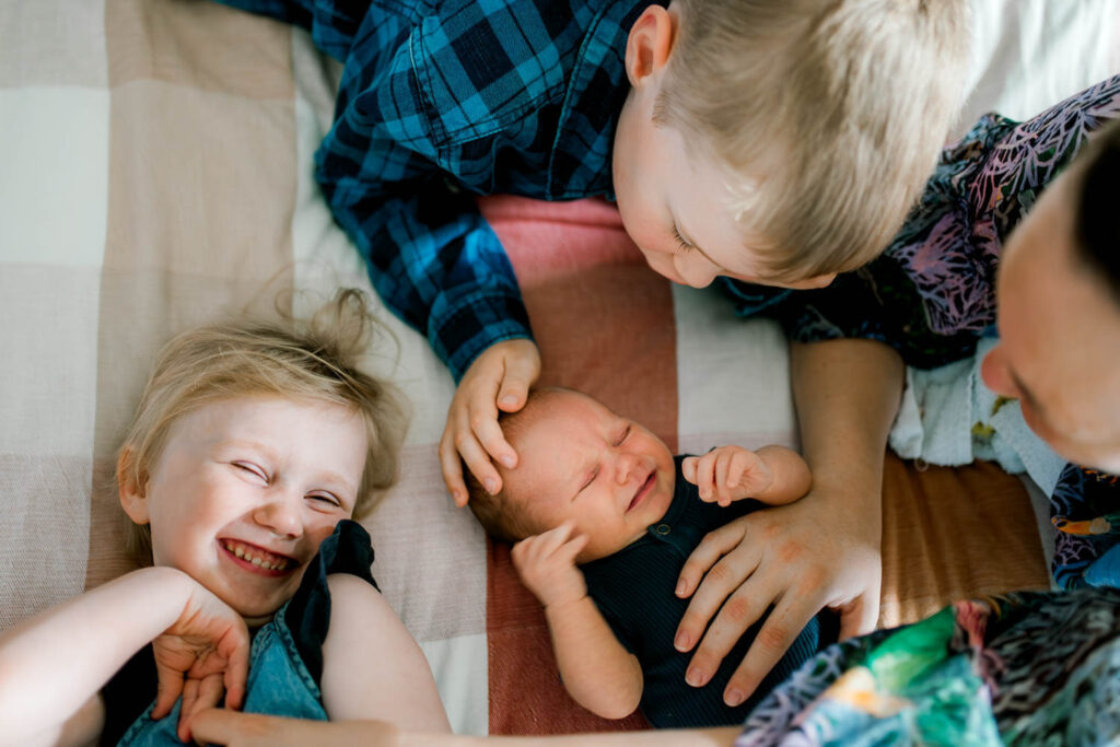 Newborn baby surrounded by older siblings and mum
