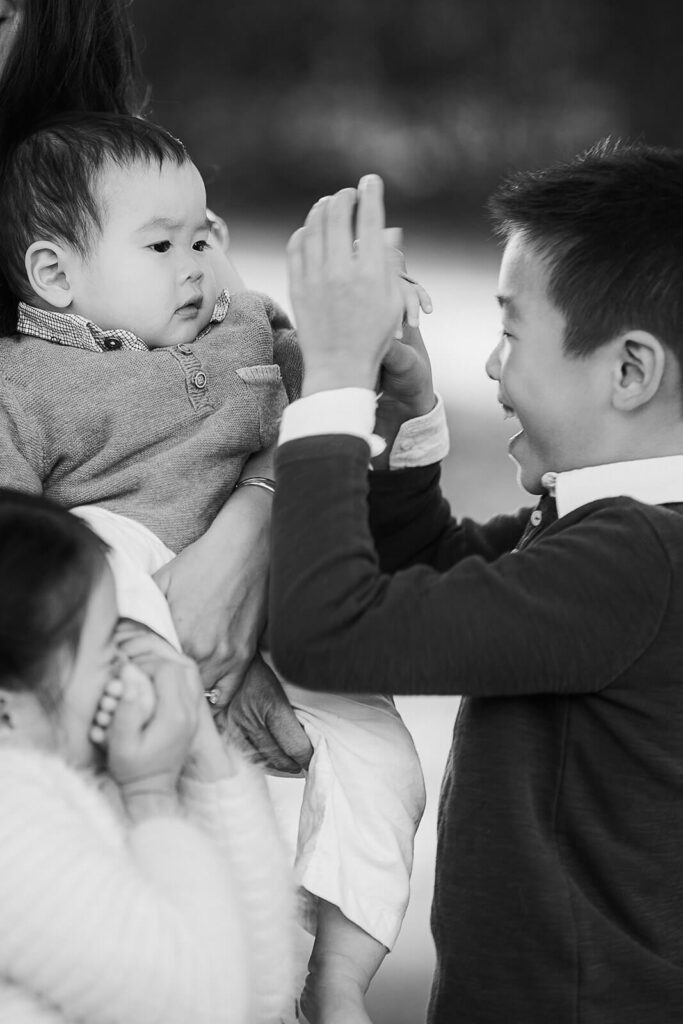 Siblings playing with baby brother in the garden