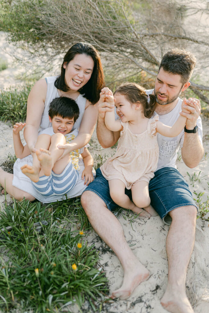Natural candid family moment in a grassy park wearing timeless clothes