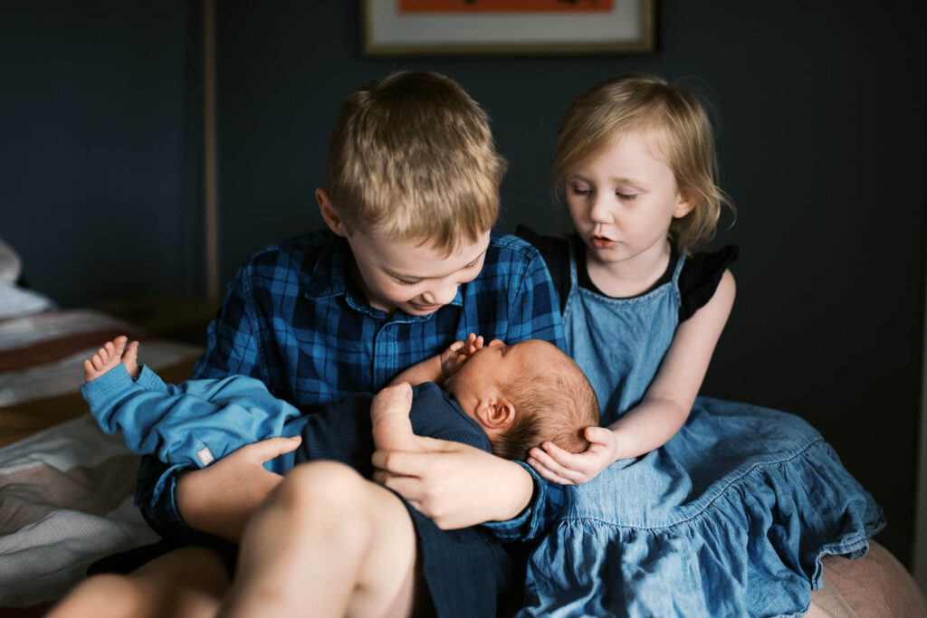 Older siblings meeting newborn baby at home during Sydney in-home newborn photography session