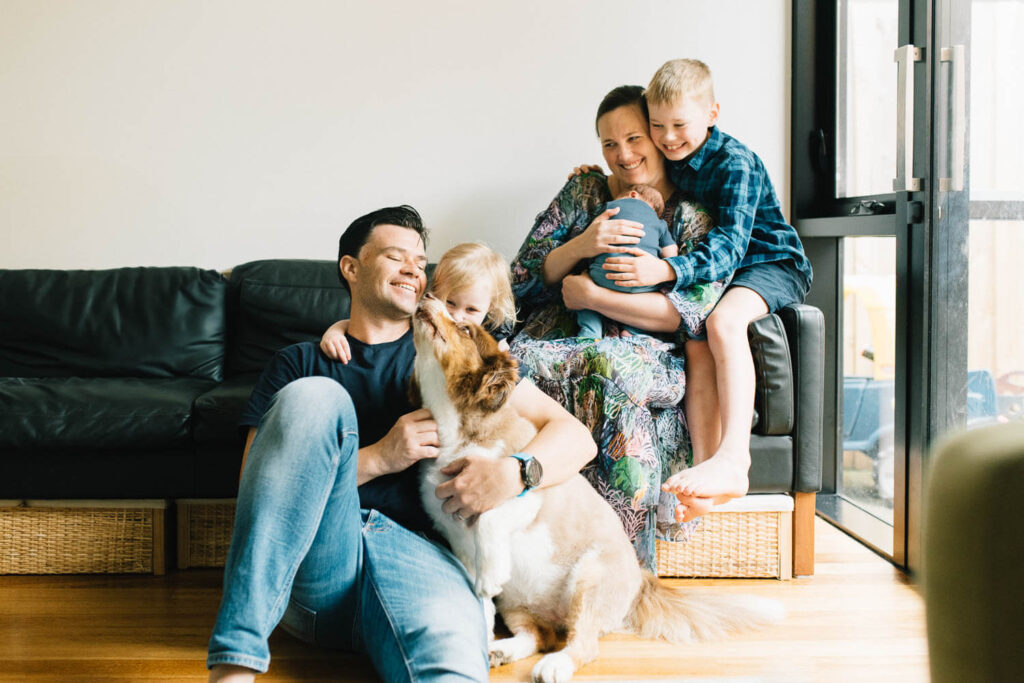 Sydney in-home newborn photographer capturing parents and toddler cuddling newborn on the couch at home