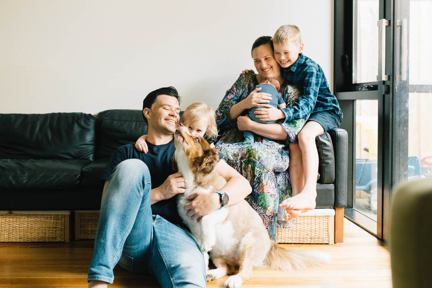 Sydney in-home newborn photographer capturing parents and toddler cuddling newborn on the couch at home