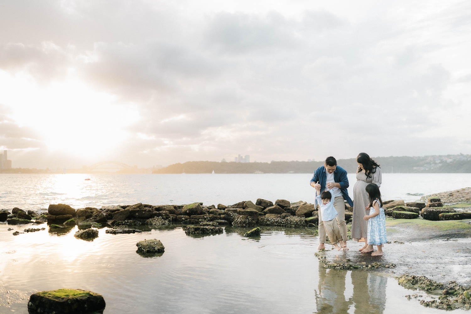 Young family of four playing at the beach at sunset