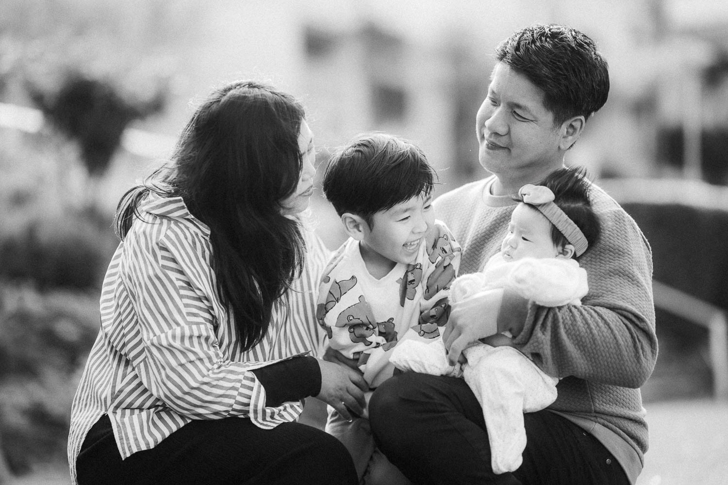 Family of 4 playing with newborn baby at the garden