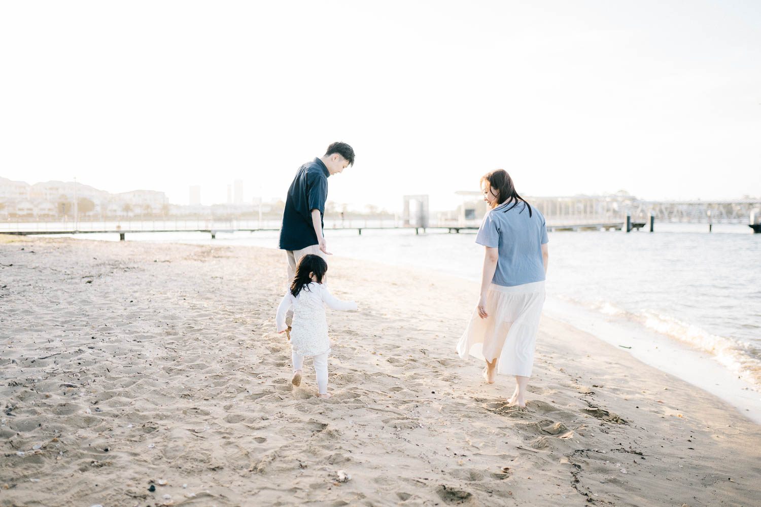 Family with toddler playing by the river in the afternoon at Cabarita Park in Sydney Inner West