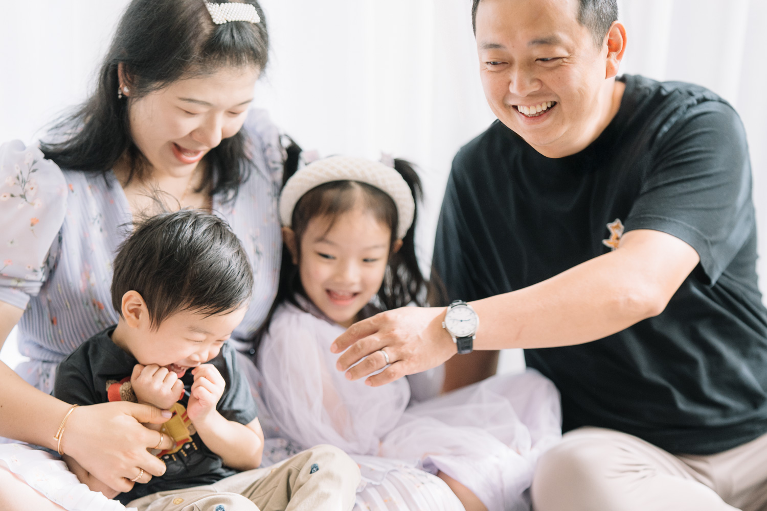 Young family of four playing tickles at home on a relaxing morning