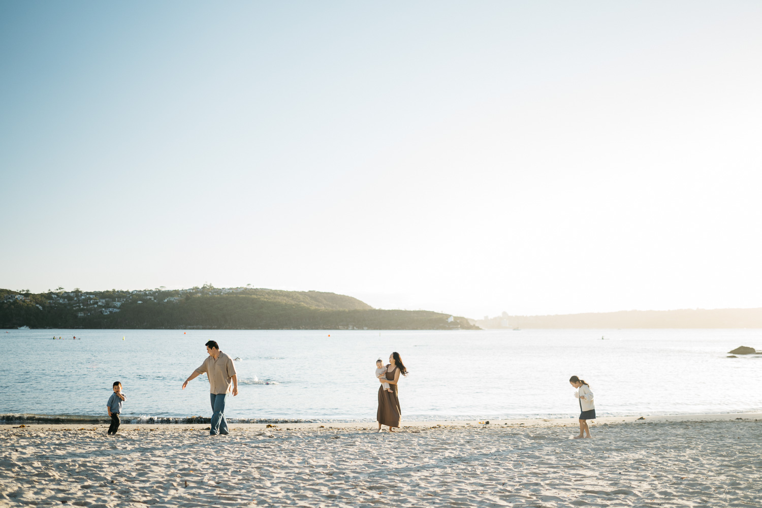 Family of five having fun running together at a Sydney beach during sunrise